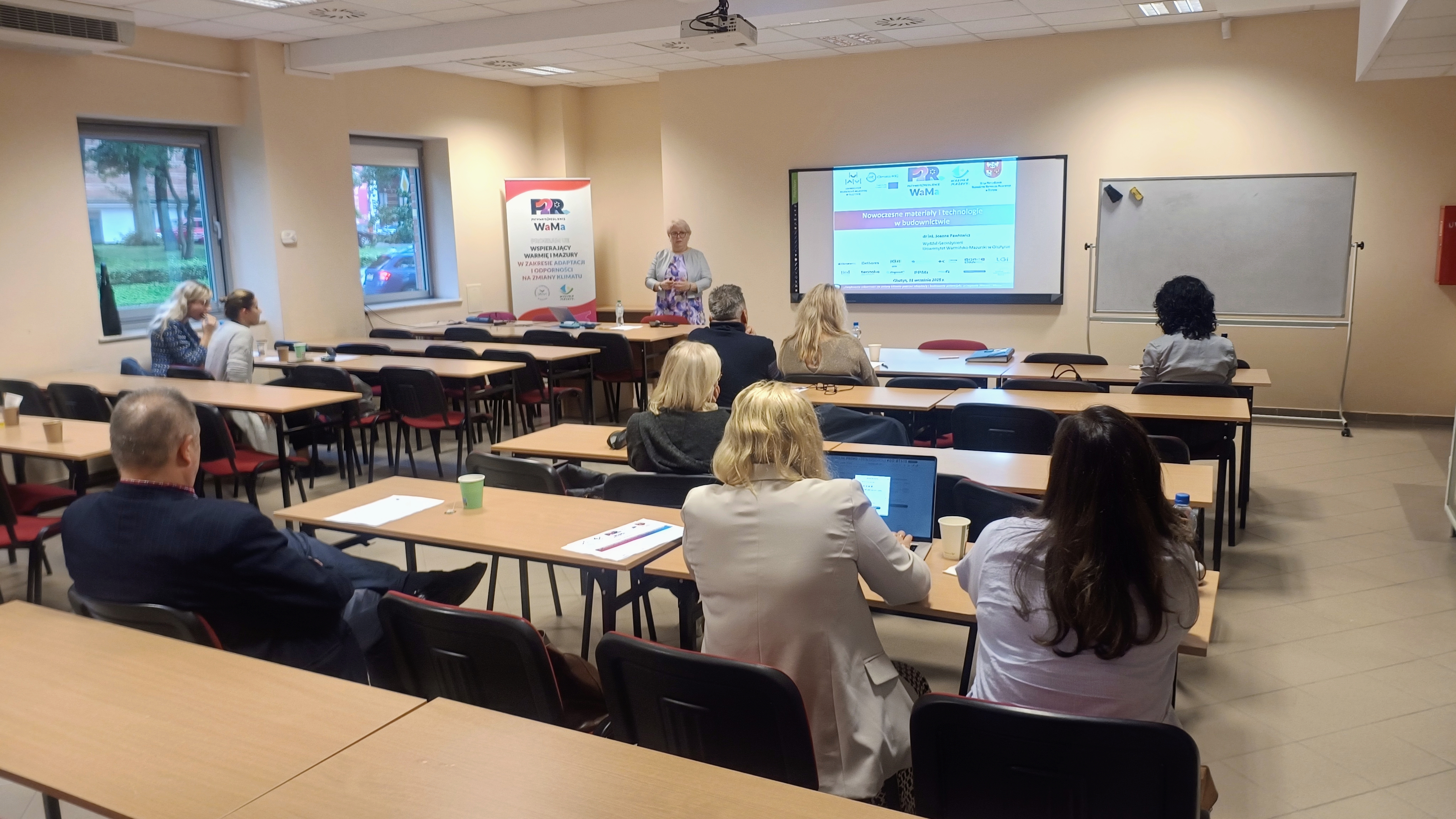 zdjęcie przedstawia sale wykładową na której prowadząca zwrócono jest twarzą do grupy słuchaczy